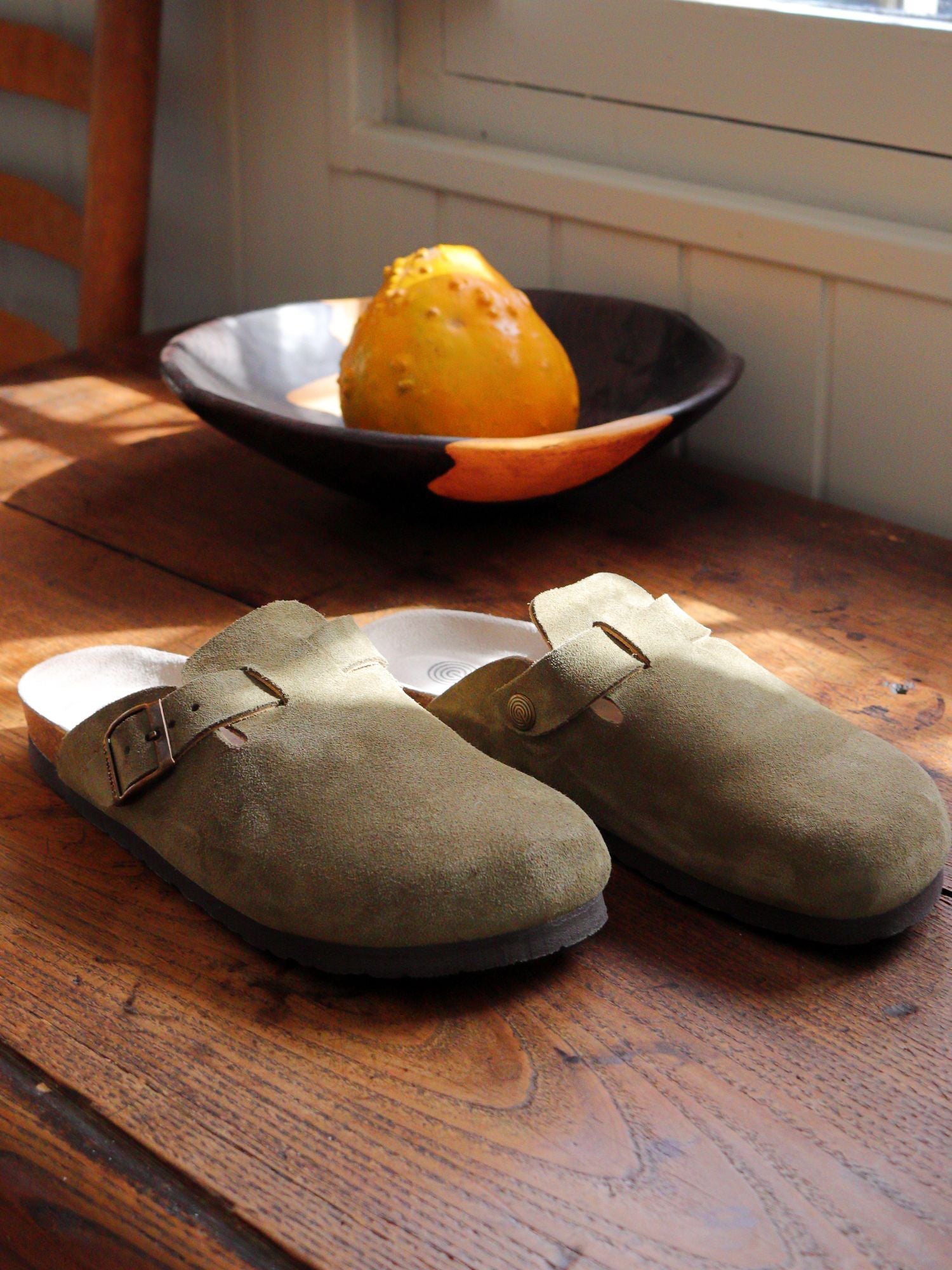 Zueco Genuins Riva  de piel serraje color kaki con planta anatómica de caucho corcho y hebilla ajustable metálica para hombre bodegón